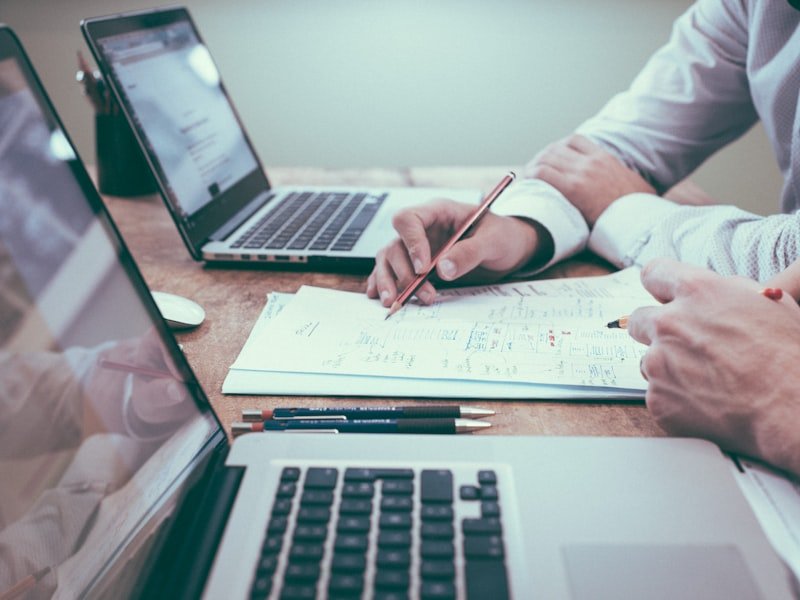 Hand reviewing a chart with two laptops — HST filing and ITC optimization